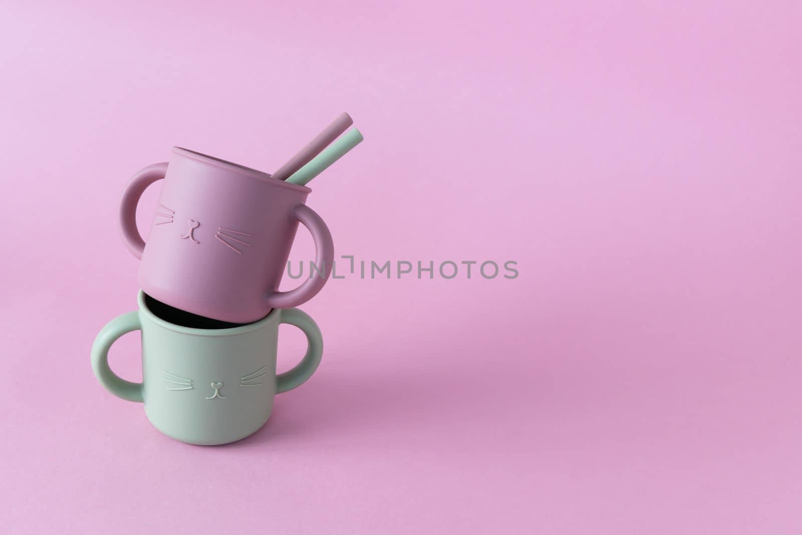 Modern pastel color silicone sippy cups with straws on pink background. Baby tableware, first feeding, serving concept.Space for text. by Ri6ka