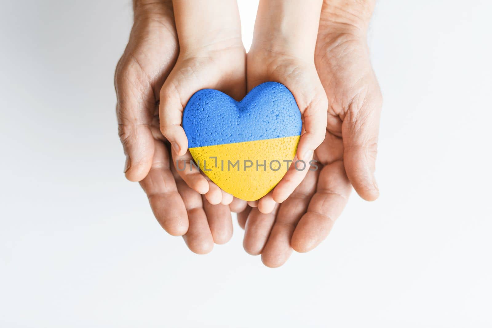 male hands hold childrens with painted yellow and blue heart on white background. concept needs help and support, truth will win