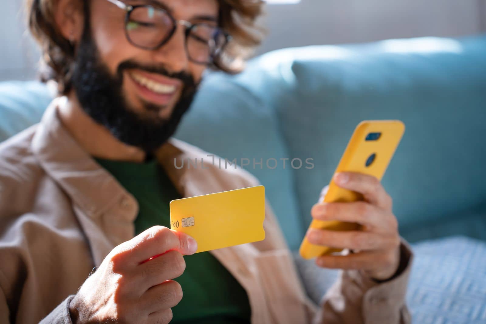 Happy Caucasian man buying things online, using smartphone and credit card, shopping in internet by PaulCarr