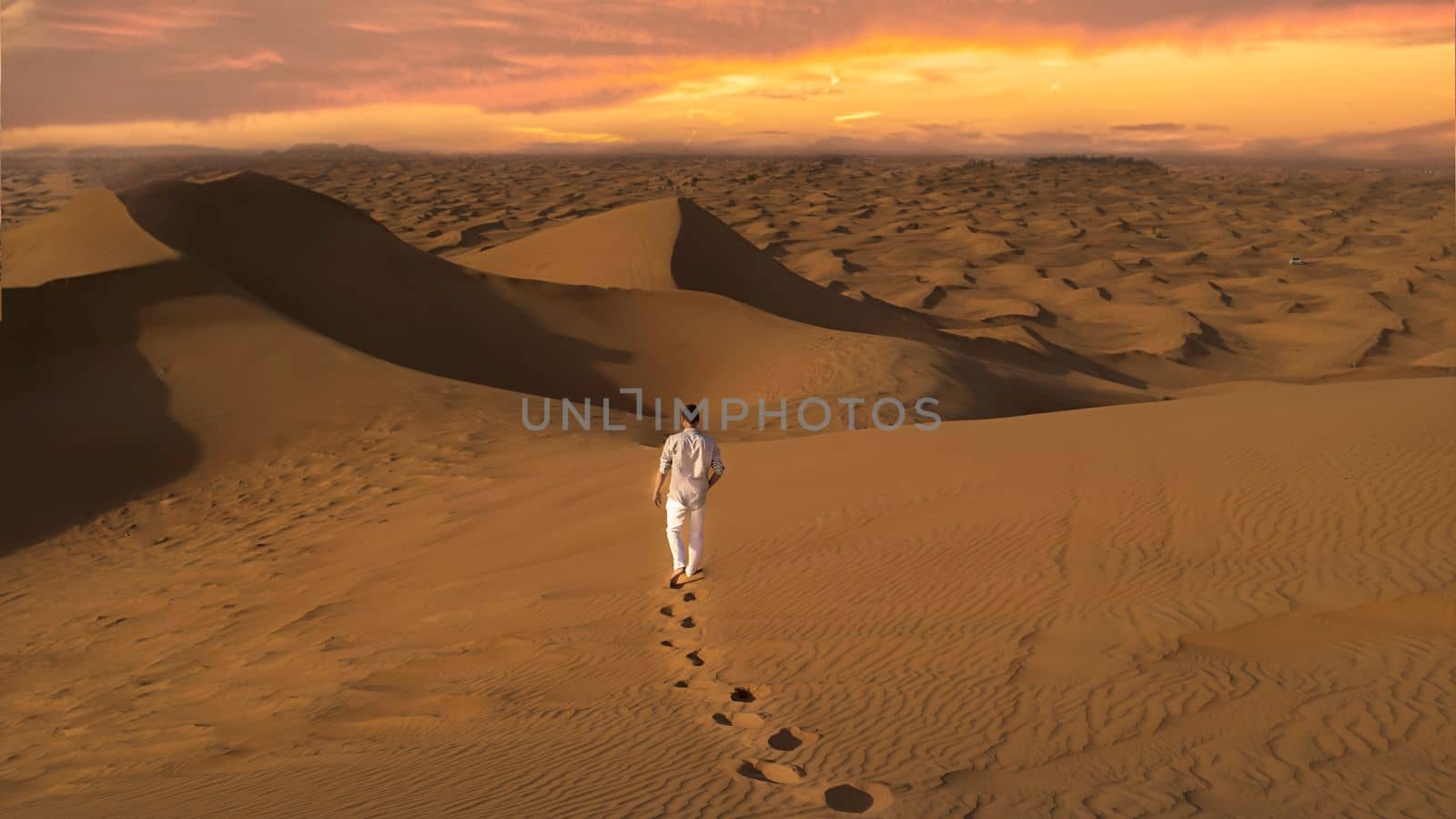 Dubai desert sand dunes, men watching sunset in the Dubai desert safari,United Arab Emirates, by fokkebok