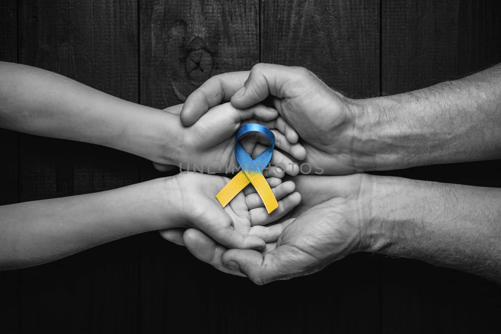 children hands in male hands with ukraine ribbon by alexxndr