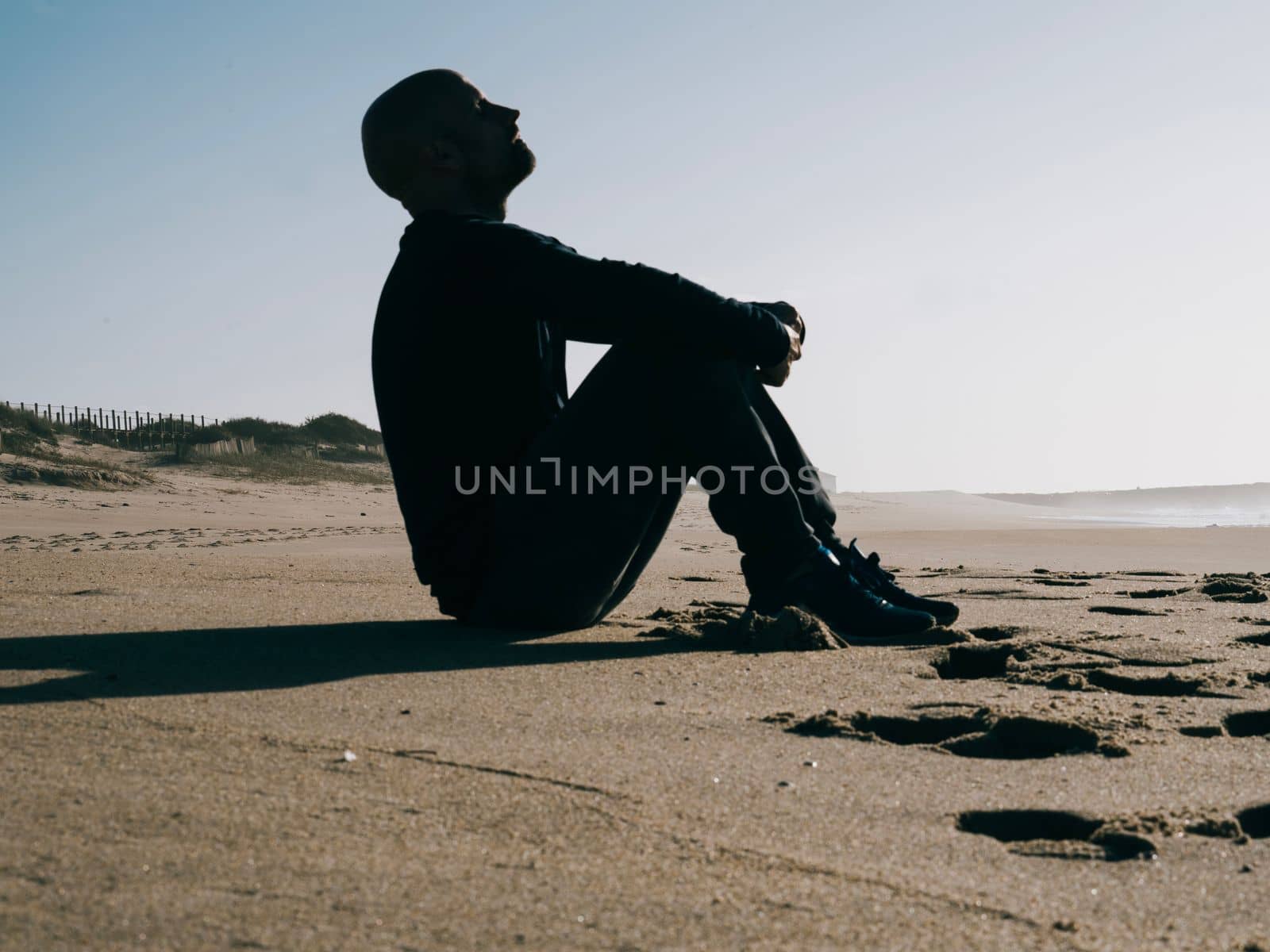 Silhouette of a young man breathing deep fresh air on the beach with copy space.