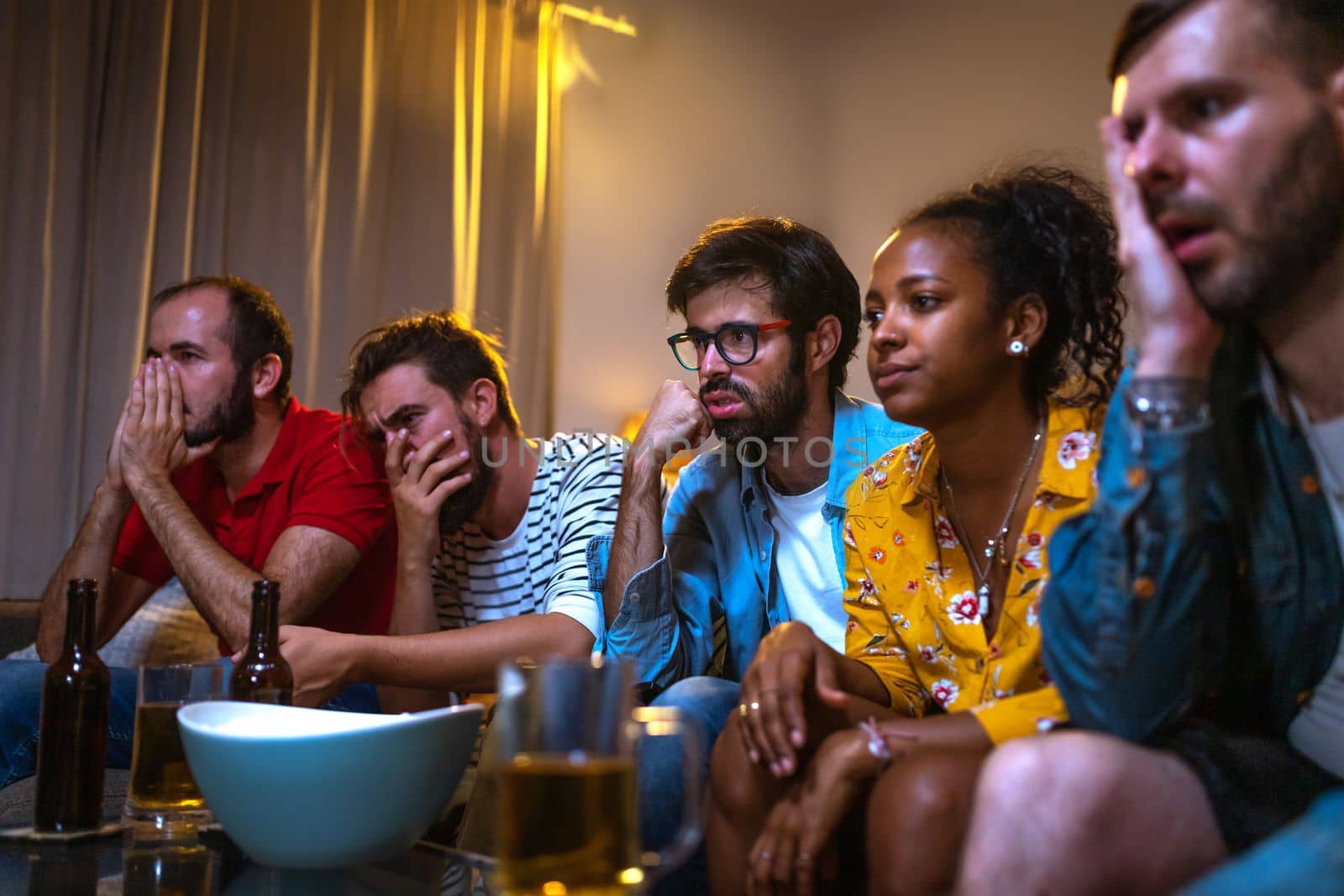Group of friends watching football game on tv worried and sad because their team is losing. Soccer. Leisure activities concept.