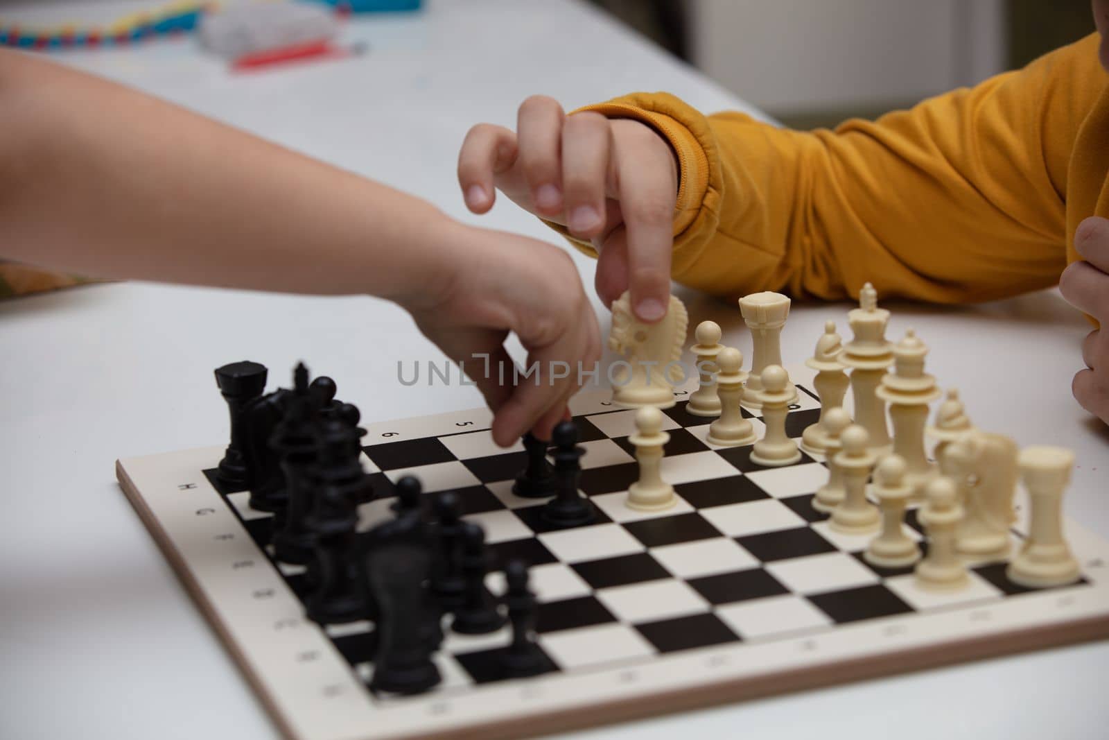 sits at a table and plays chess. The kid concentrated on the game and thinks where to make his next move. Early development, home educational games for children by senkaya