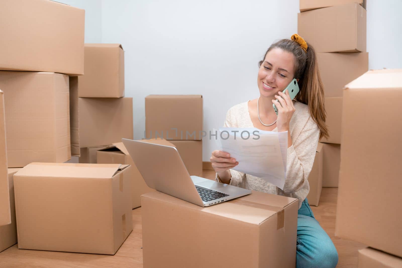 Beautiful girl with cardboard boxes unpacking in new home - Working with laptop by PaulCarr