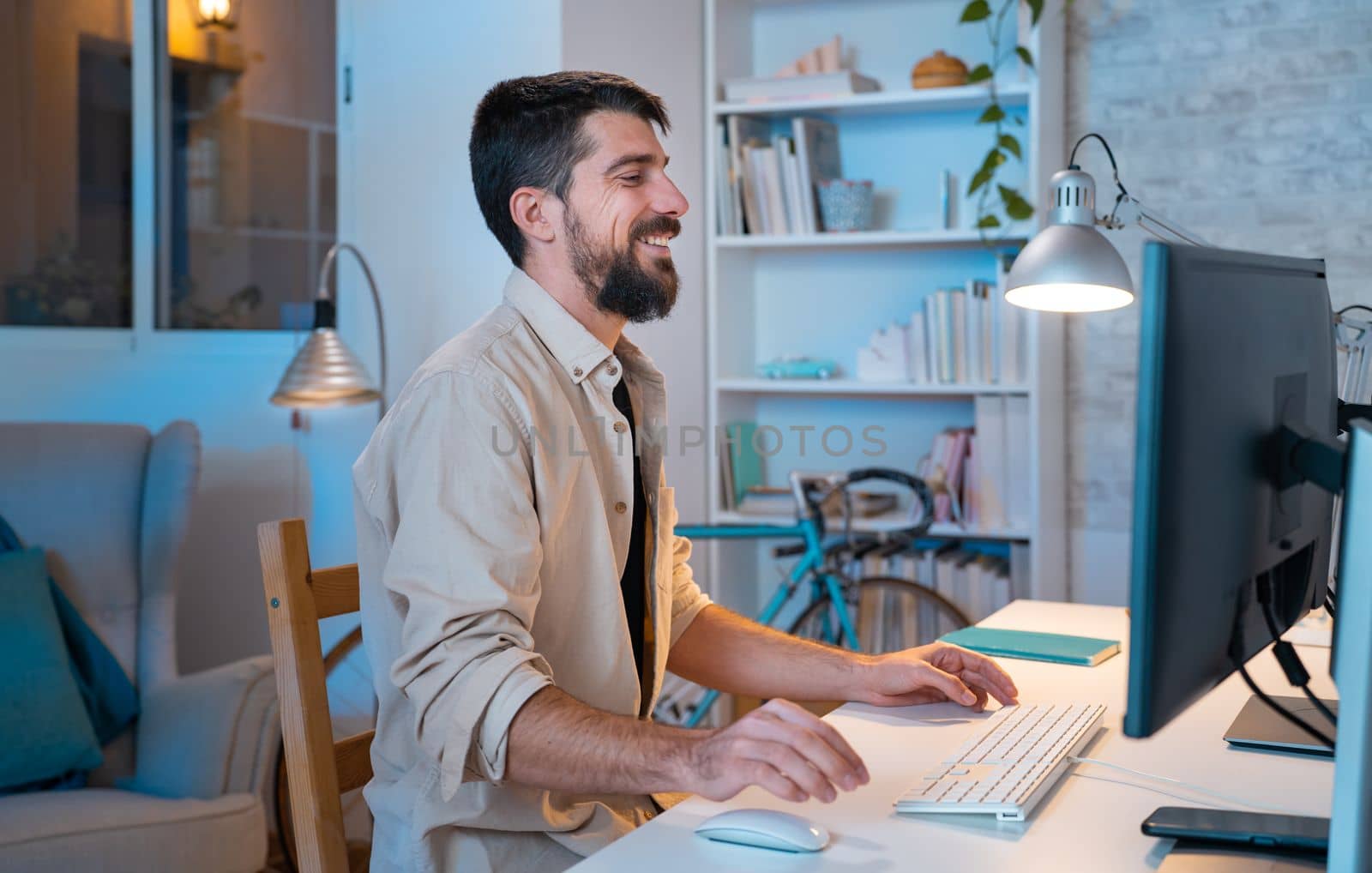 Young creative entrepreneur happy smiling while working in his modern workspace at home. - Freelance guy small business, work from home concept. High quality photo
