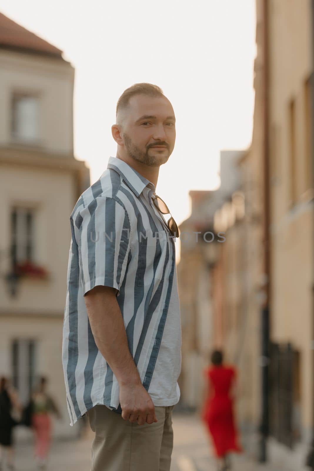 A portrait of a middle-aged male tourist in the streets of an old European town. A man in a shirt and shorts in Warsaw in the evening.