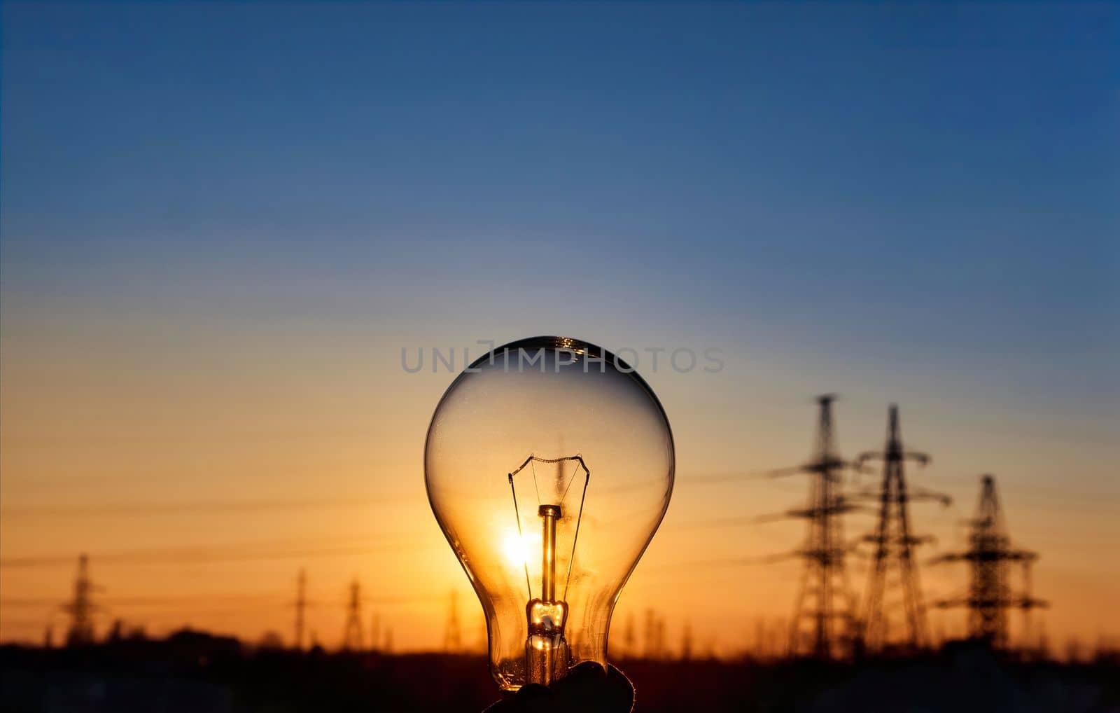 Light bulb with high voltage line on background. Electricity and energy savings in the city .