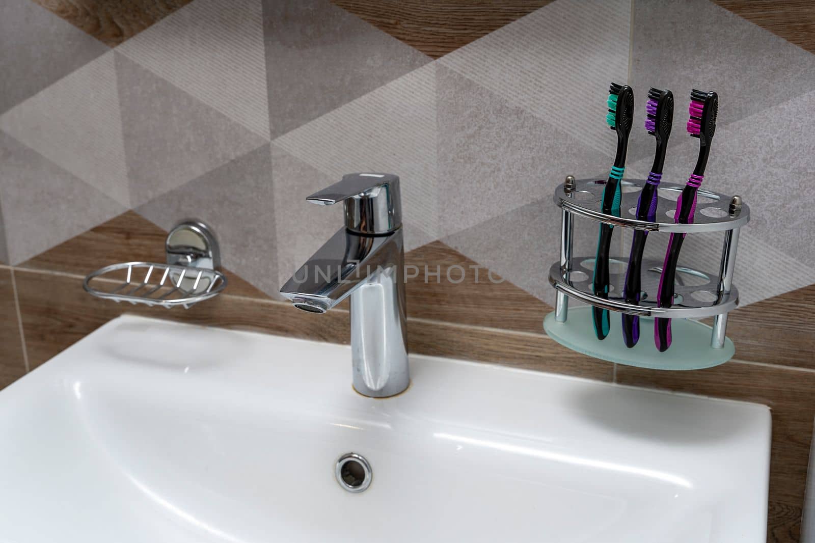 toothbrushes stand on a special stand in the bathroom interior. a sink, a soap dish and a modern mixer are visible. products for daily hygiene