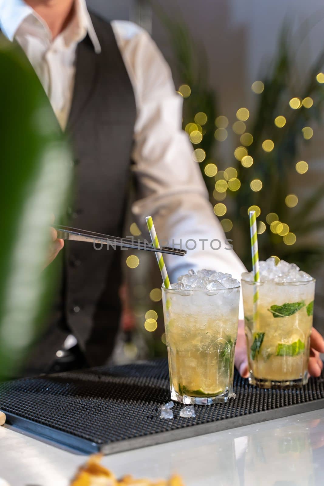 Unrecognizable barman making cocktail Mojito in night club adding ingredients and creating expert drinks on bar counter. High quality photo