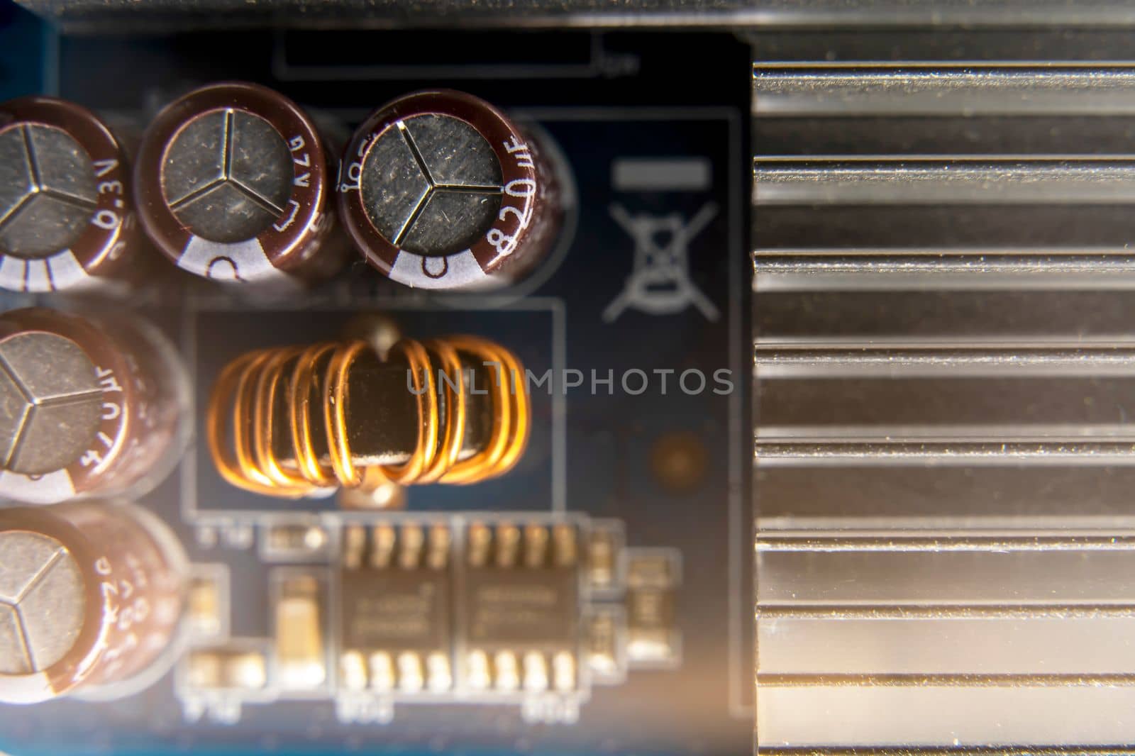 Background of various electronic components on a blue printed circuit board in close-up. Ferrite core of a toroidal inductor wrapped with copper wire, resistors and capacitors on a blue printed circuit board. The concept of electro and microprocessor technologies. aluminum Cooling radiator Selective focus