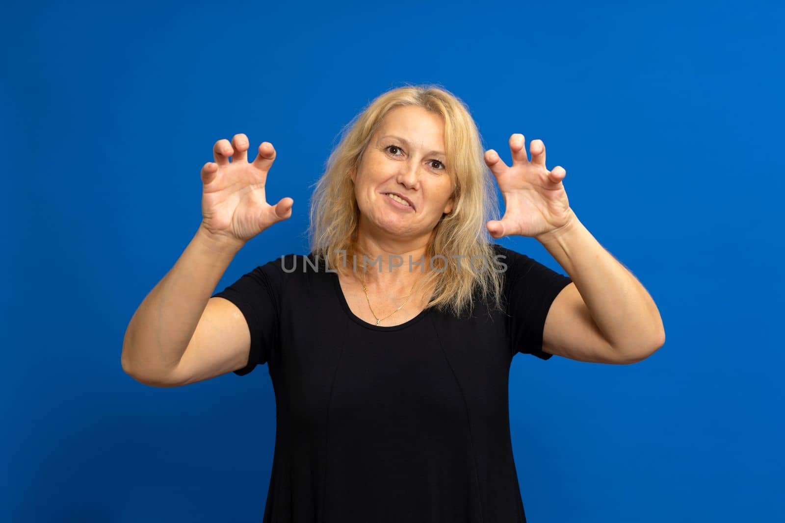 Photo of caucasian attractive blonde woman fooling show fingers claws lion growl isolated over blue color background