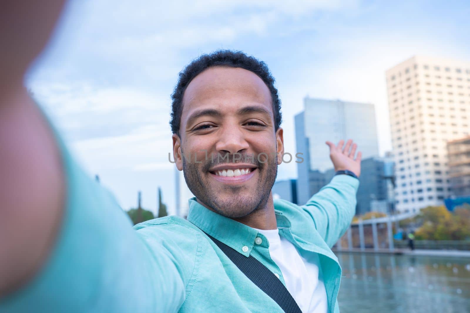 Young African American man taking a selfie smiling happy showing the new city where he lives. Tourist traveling around the world concept. High quality photo