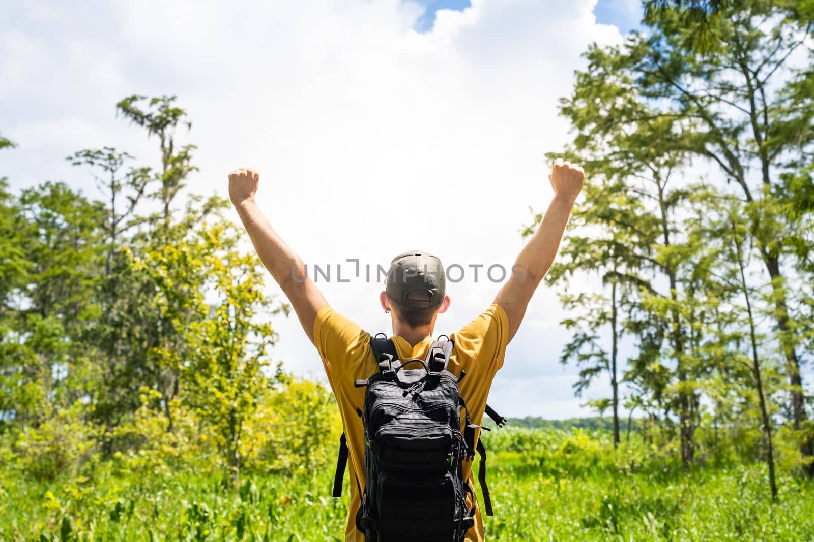 Male traveller with raised hands of happiness in the nature woods. Travel lifestyle freedom concept. High quality photo