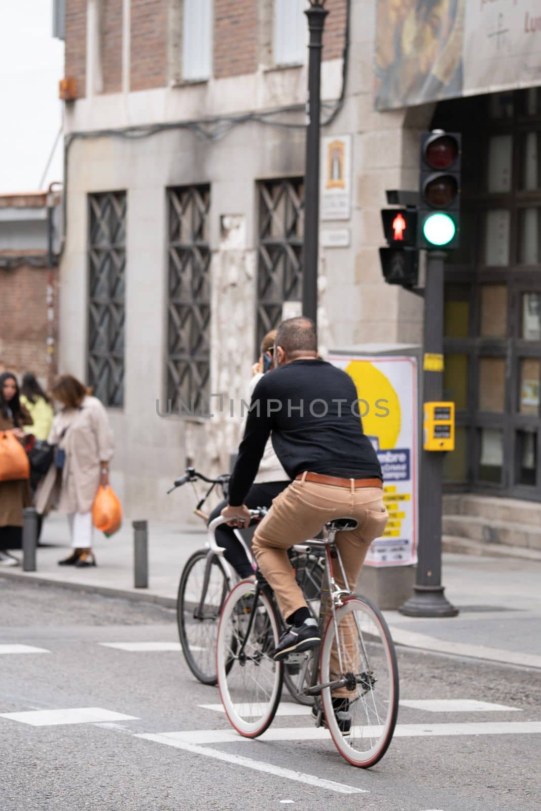 People driving a bicycle in Madrid city center road. Sustainability and ecology concepts by papatonic