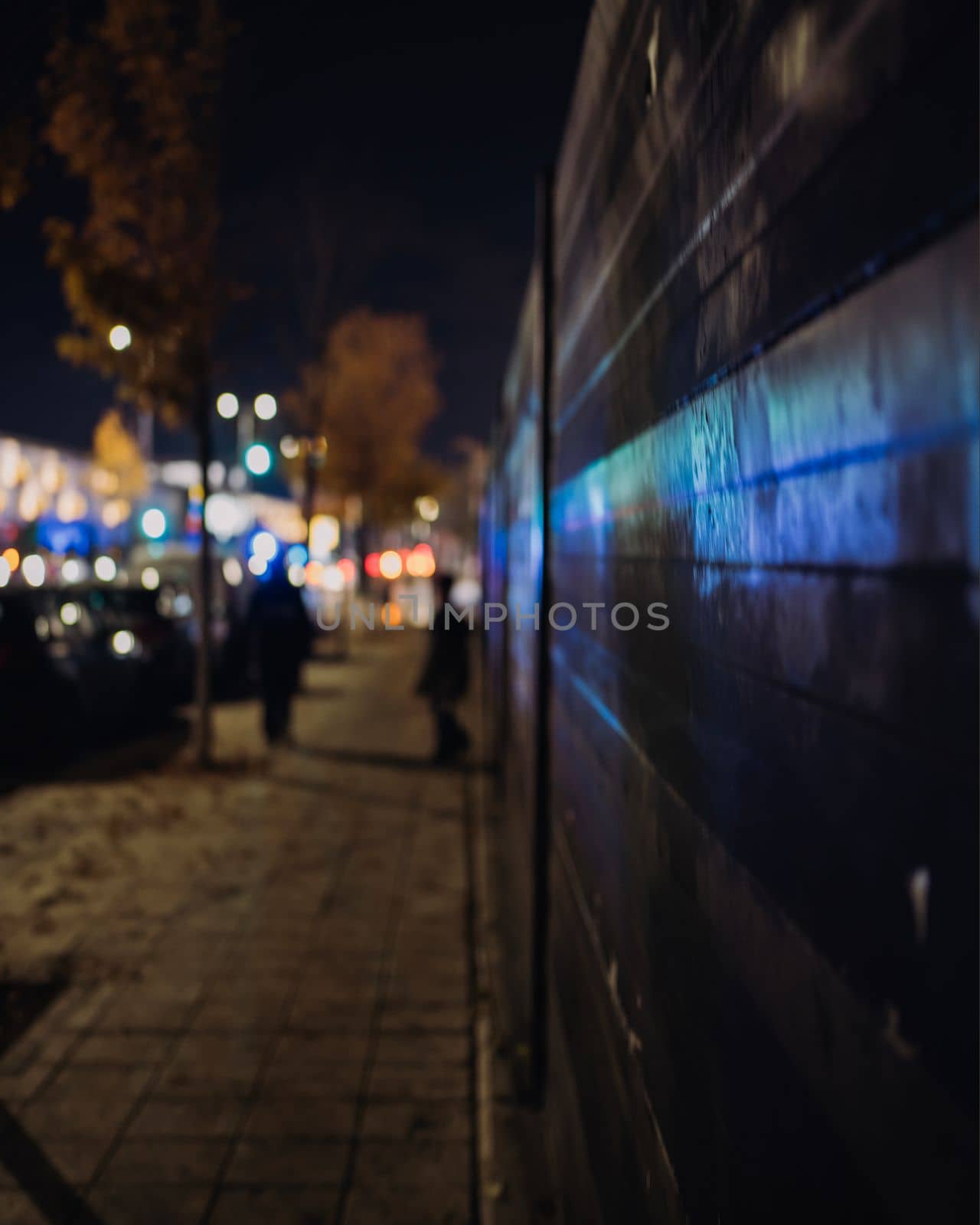 Abstract concept of Blue and red emergency lights in background reflecting on street metal wall. Boys in silhouette discussing what could happen.