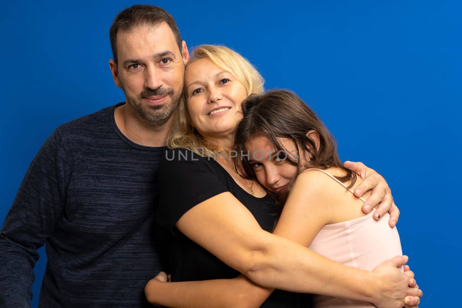 Portrait of happy parents, mom, dad with teenage daughter sweaters isolated blue studio background. Family day fatherhood concept