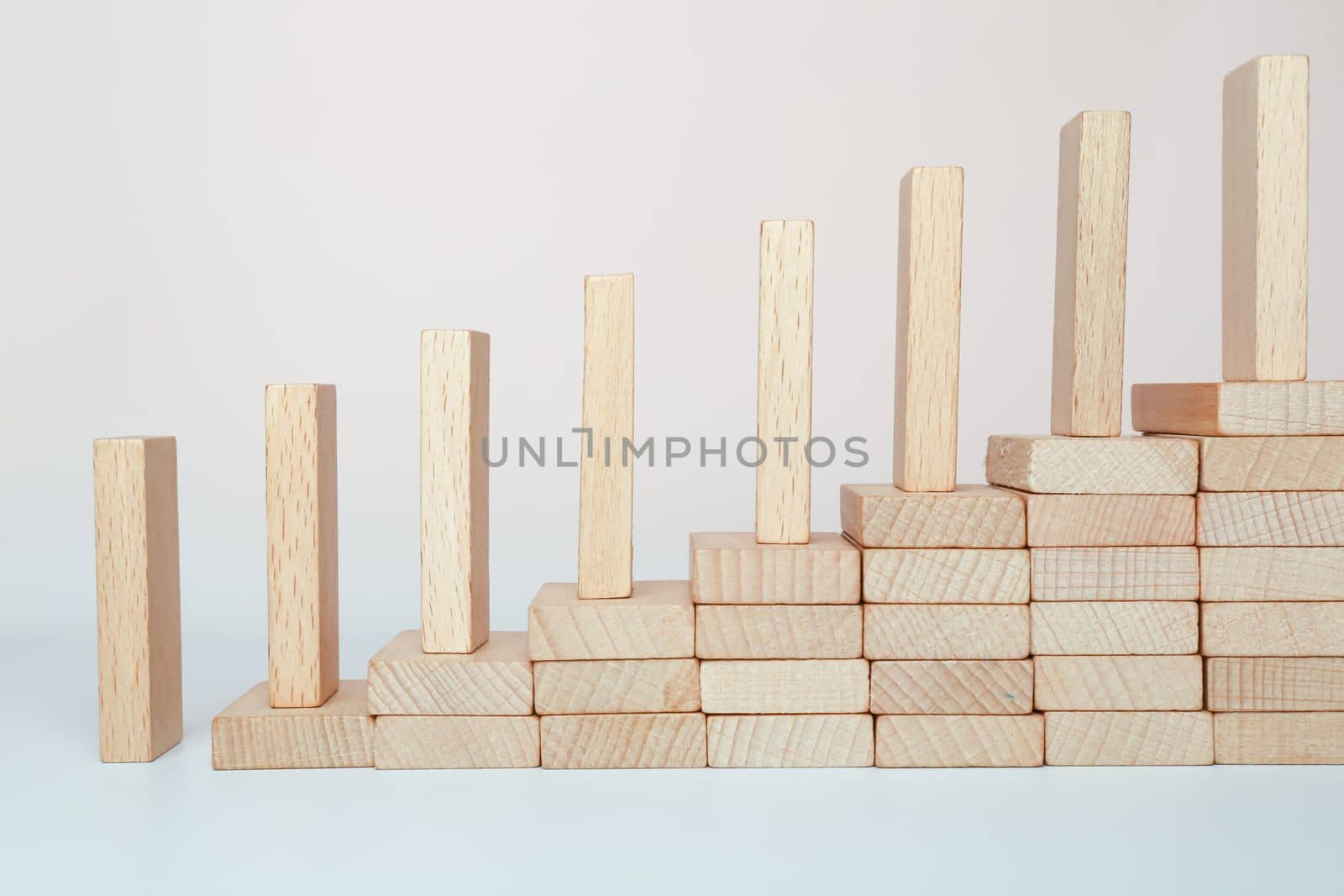 Domino effect climbing the stairs on a wooden staircase lined with steps. Business management ideas for sustainable growth and profitability.