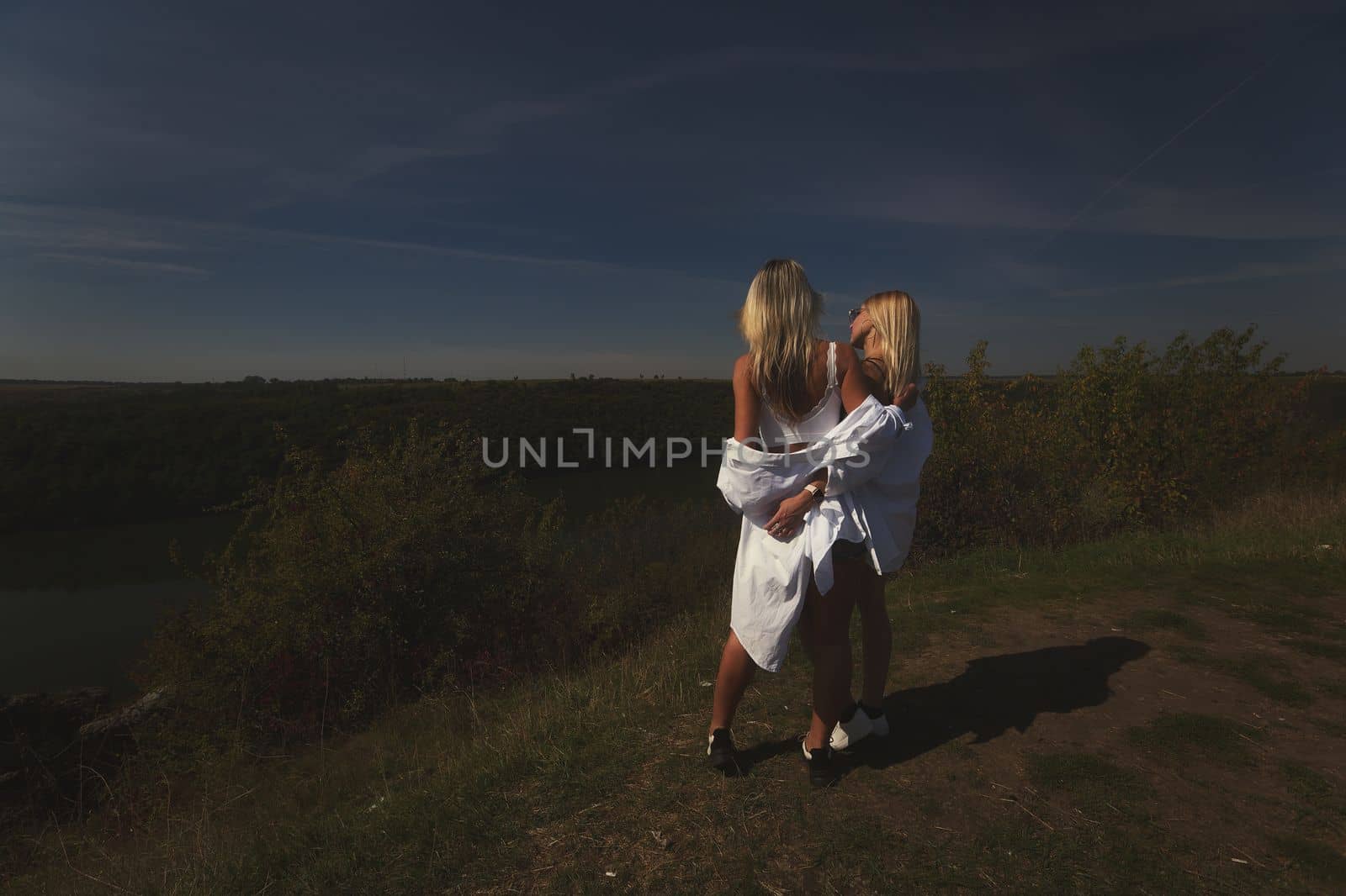 two best friends take a break from work, feel free and enjoy privacy. Blonde sisters in nature look at the landscape. Summer and good weather by marselin888