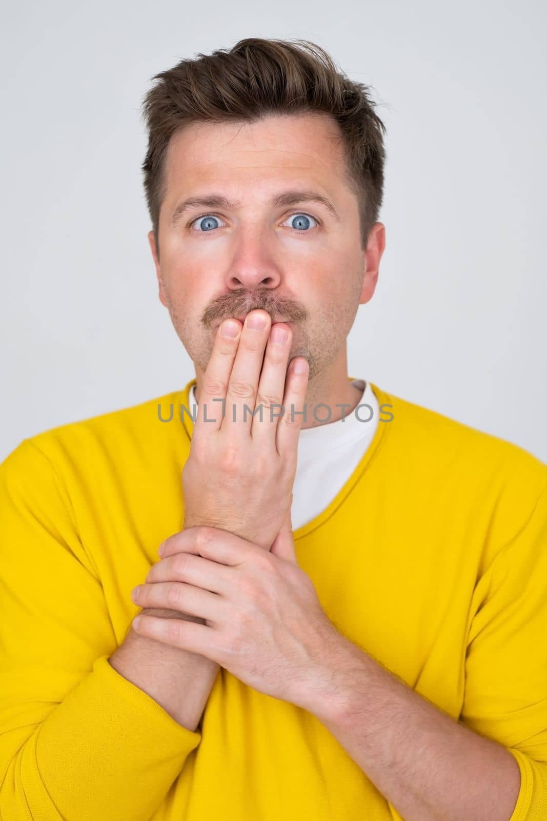 Surprised and Shocked caucasian man covering mouth with hands. Vertical orientation