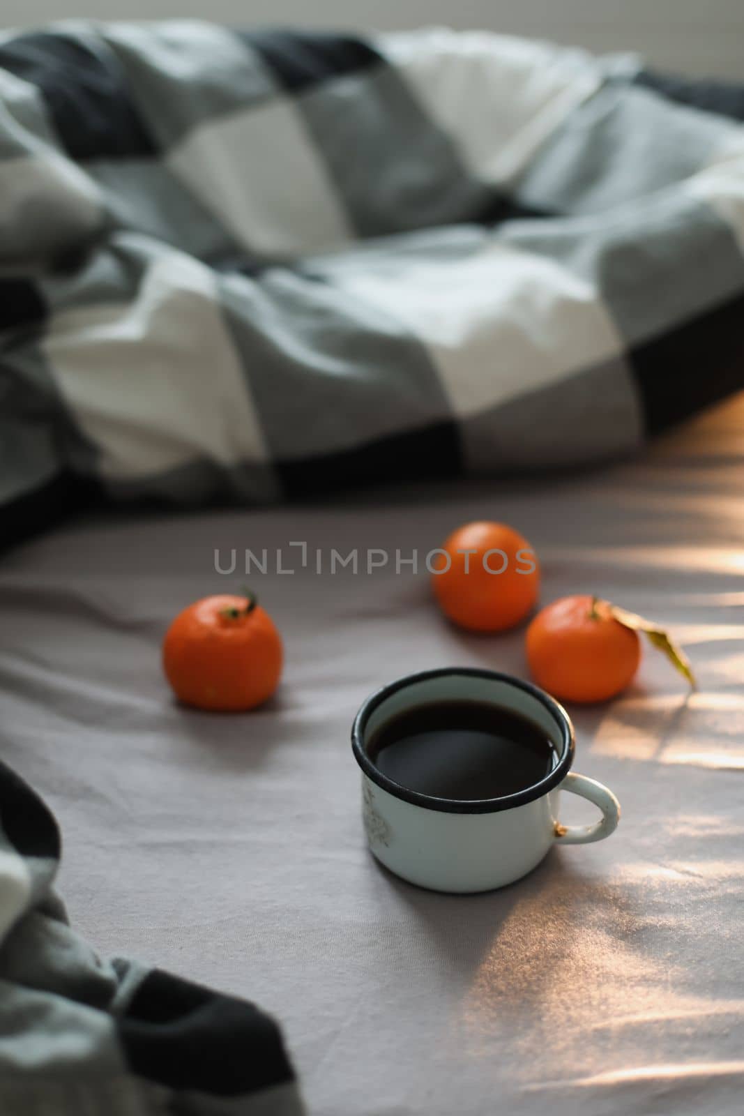Winter cozy concept. Cup with coffee and tangerines on the bed. Copy space. Flat lay, top view.