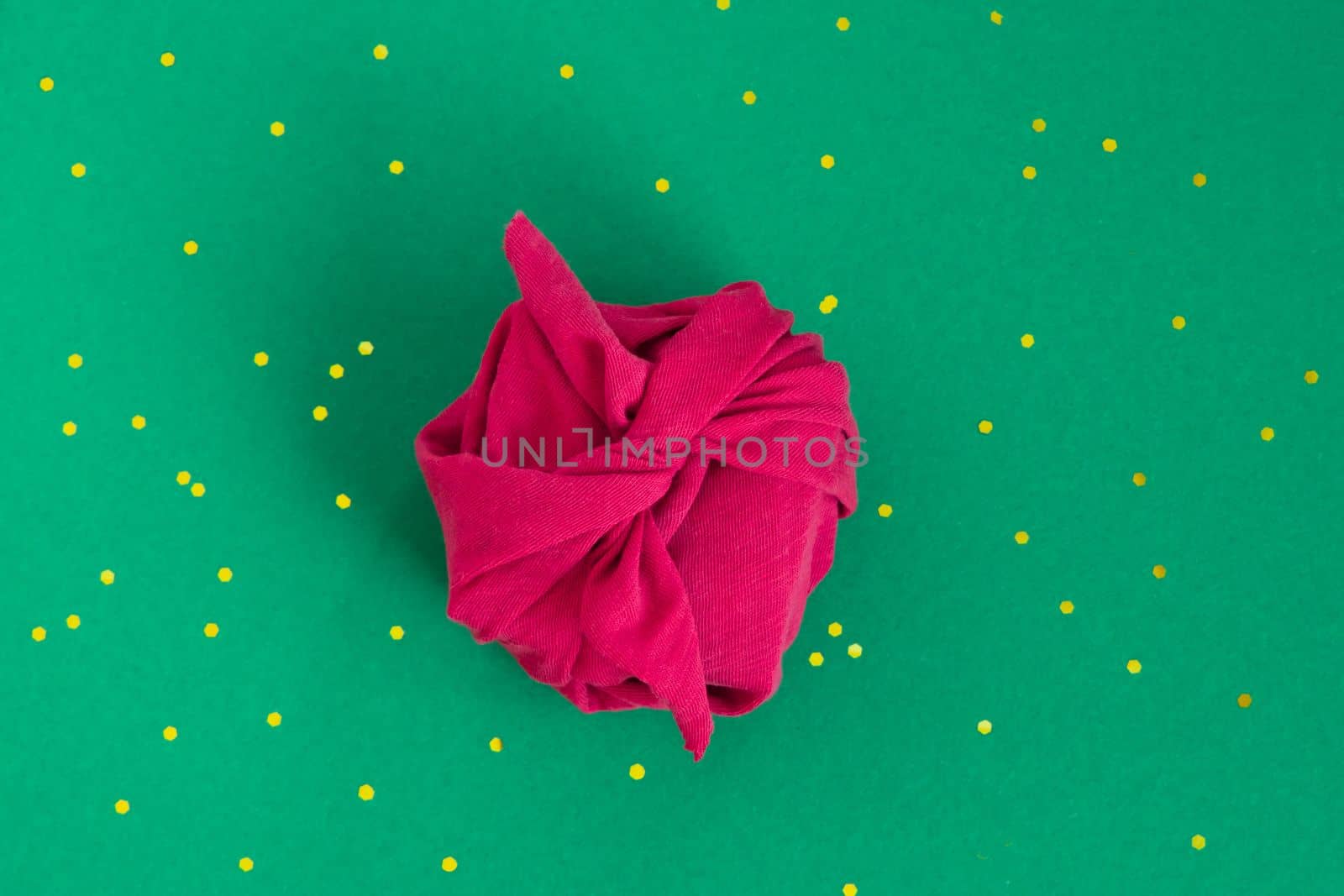 Paper free gift wrapping technique Furoshiki. Viva magenta fabric on green background. Flat lay, present box, top view. Christmas, valentines, new year concept. by Ri6ka