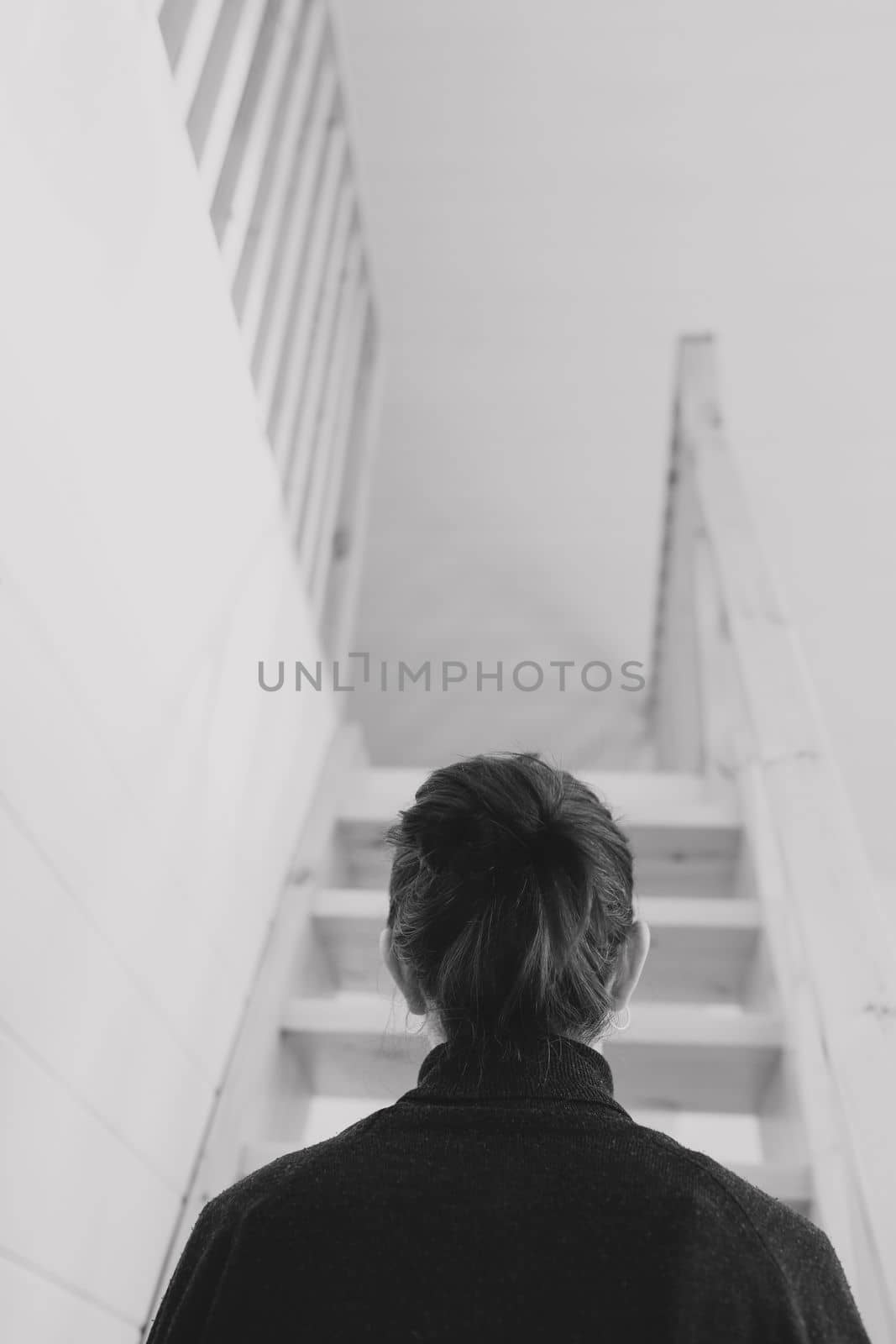 Young woman simple hairstyle back view by wooden stairs at home. Depression, loneliness and quarantine concept. Mental health, Self care, staying home. by paralisart