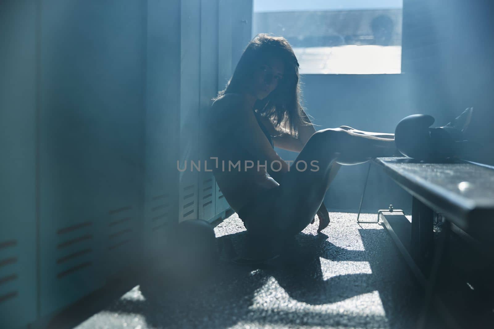 Young girl of an athletic build in the locker room of a sports club wears boxing gloves, a girl is dressed in sports black underwear, sun rays from window, sneakers by vladimirdrozdin
