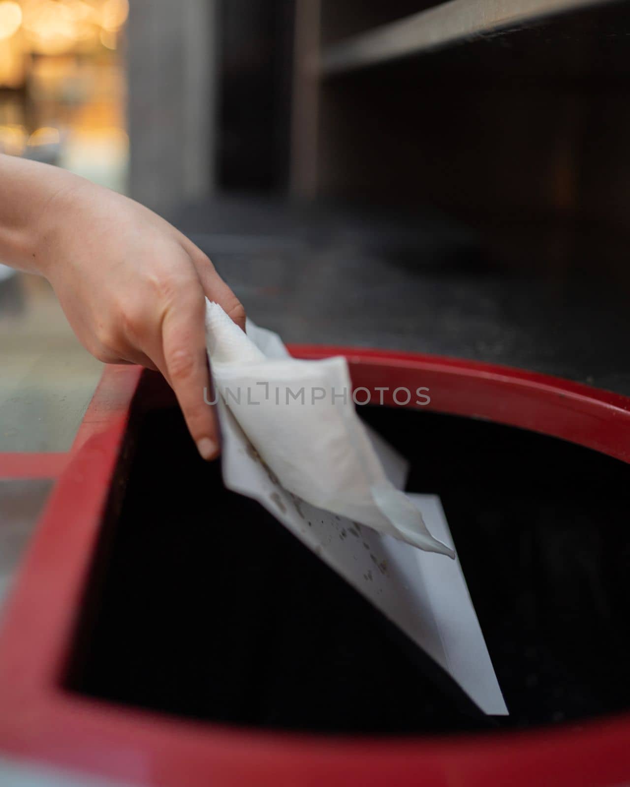human hand throwing the used white tissue paper in to a waste bin.