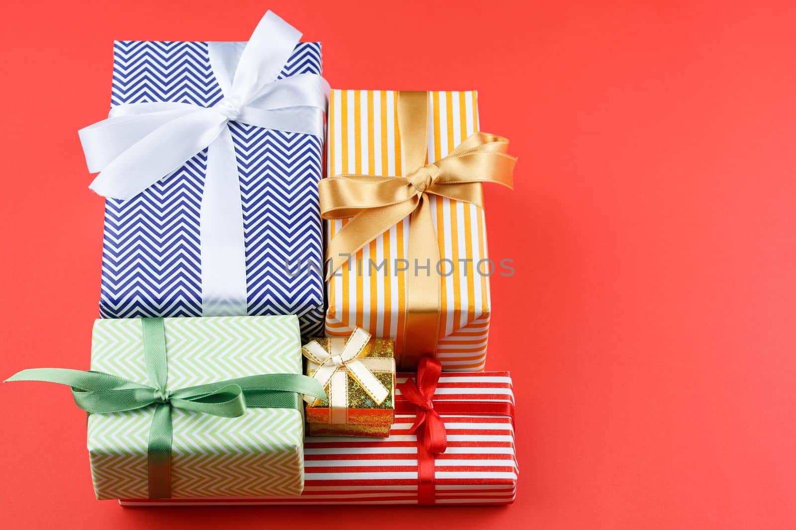 Present box in striped paper with red satin bow on red isolated background. Flat lay. Gift for a couple. Top view.