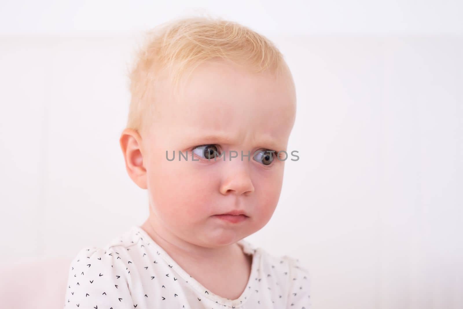 Caucasian puzzled baby frowning face lookina aside trying to remember where she put a toy