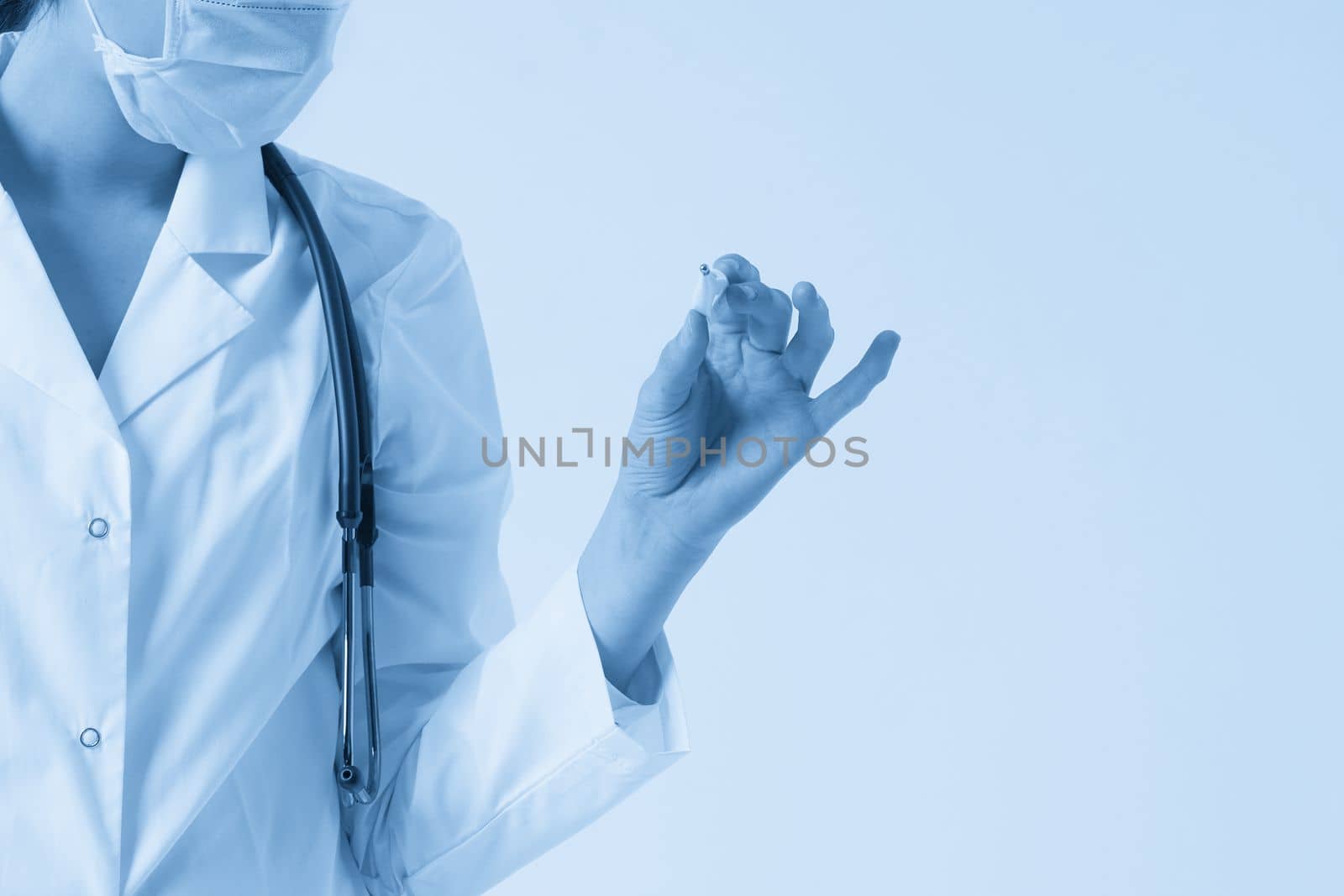 Doctor wearing face mask looking at measurement on medical thermometer over white background with copy space by Mariakray