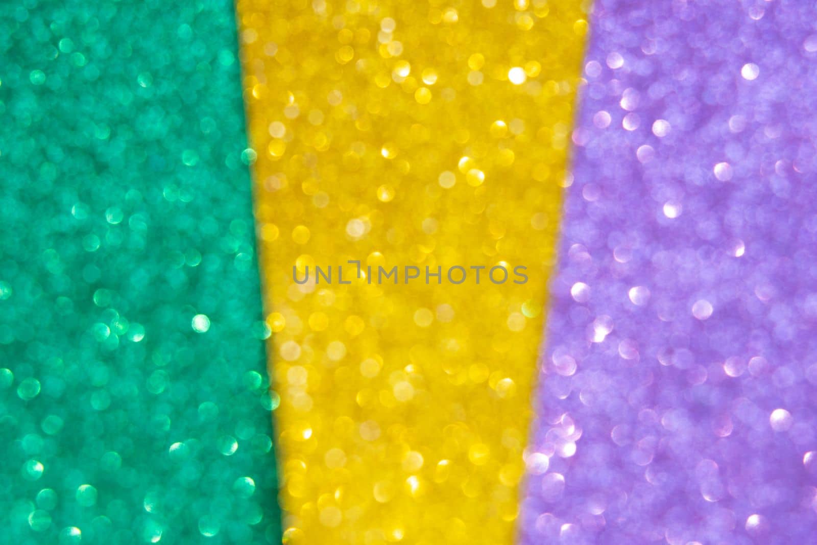 Abstract defocused shiny background gold, green, purple. Mardi gras festive traditional color background. Glow glitter Mardi gras celebration. by Ri6ka