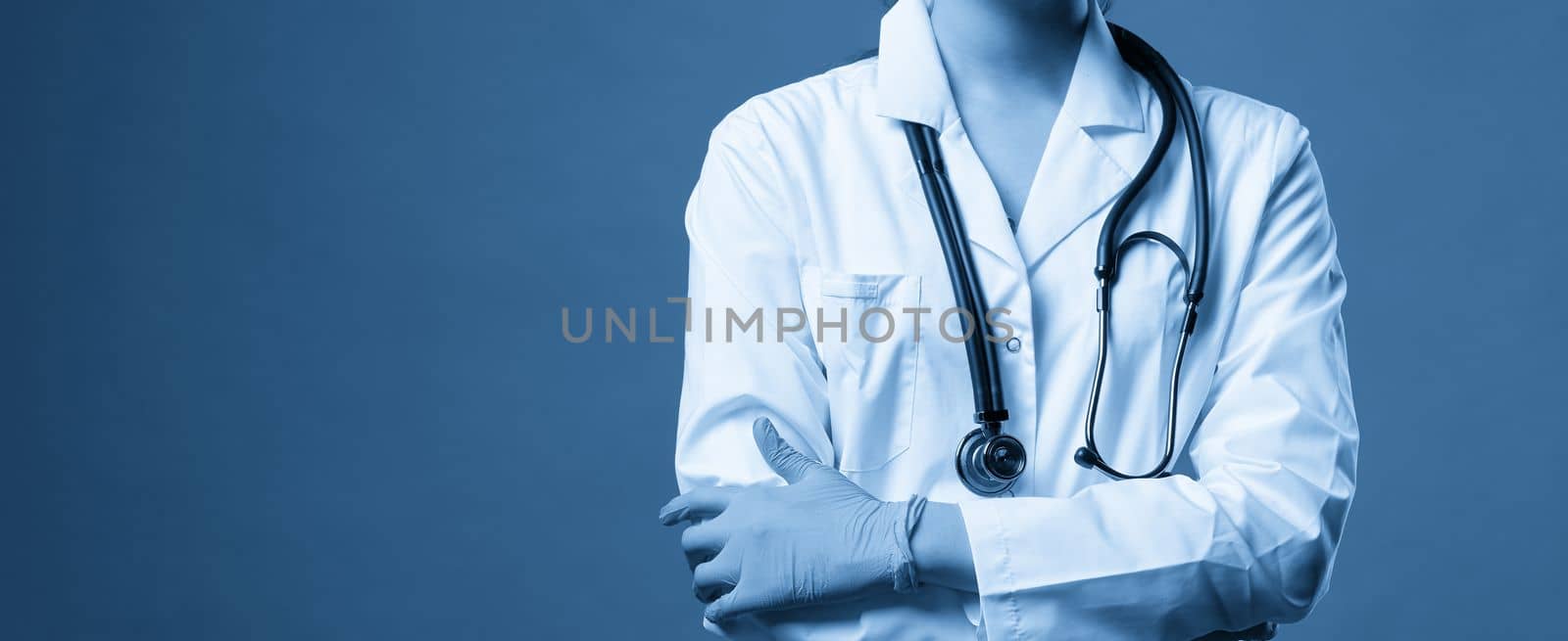 Young doctor against dark blue background, studio shot with copy space by Mariakray