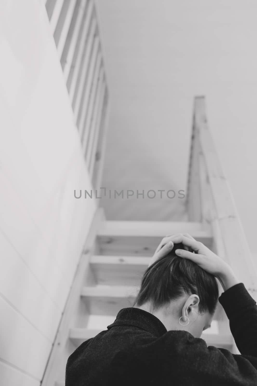 Young woman simple hairstyle back view by wooden stairs at home. Depression, loneliness, quarantine concept. Mental health, Self care, staying home