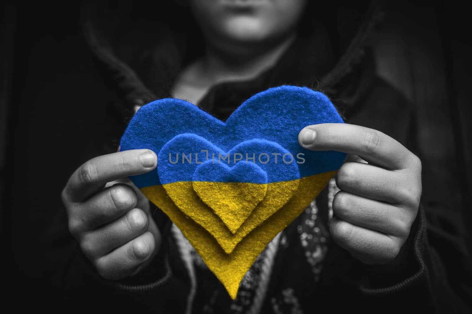 child hold painted yellow and blue heart in small hands. black and white color. concept needs help and support, truth will win