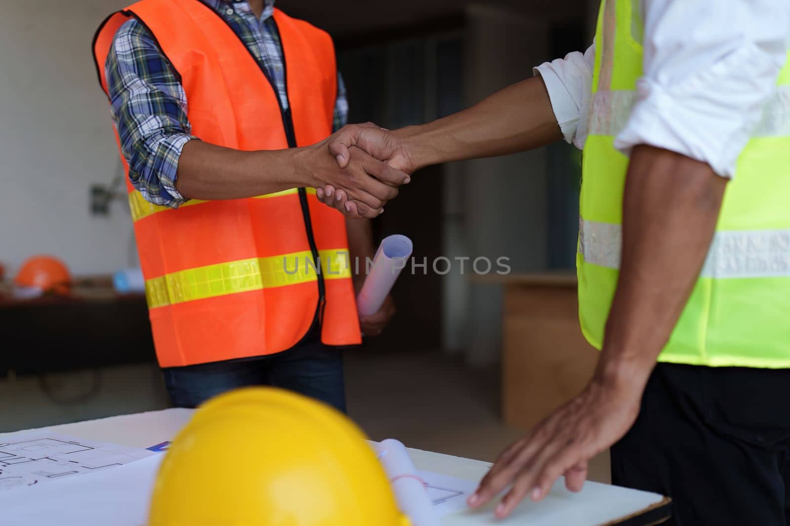 Architect and engineer construction workers shaking hands after finish an agreement in the office construction site, success collaboration concept.