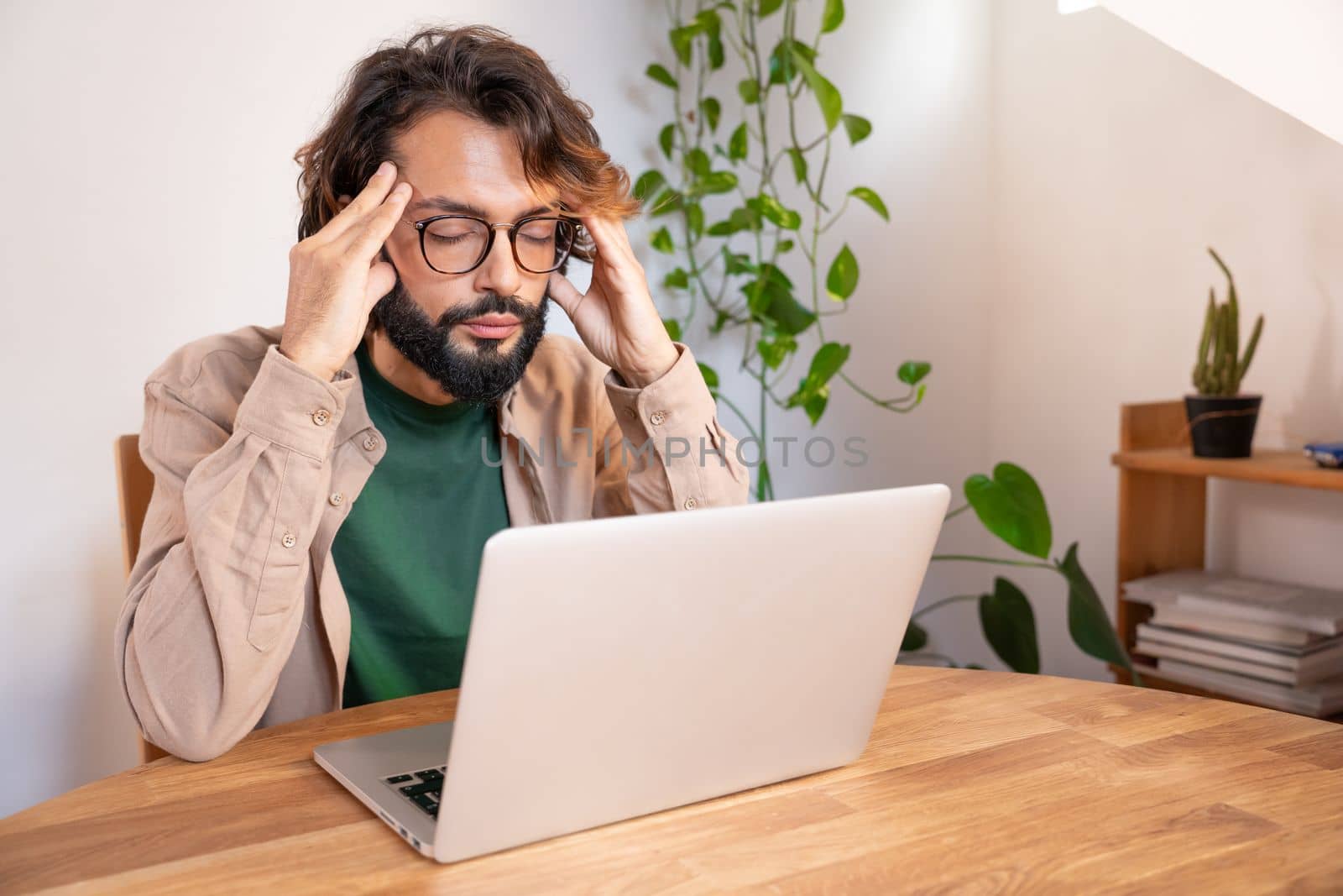 Stressed tired businessman suffering from headache working from home - Worried male entrepreneur thinking about problems and project deadline feeling burnout distress and exhausted. High quality photo