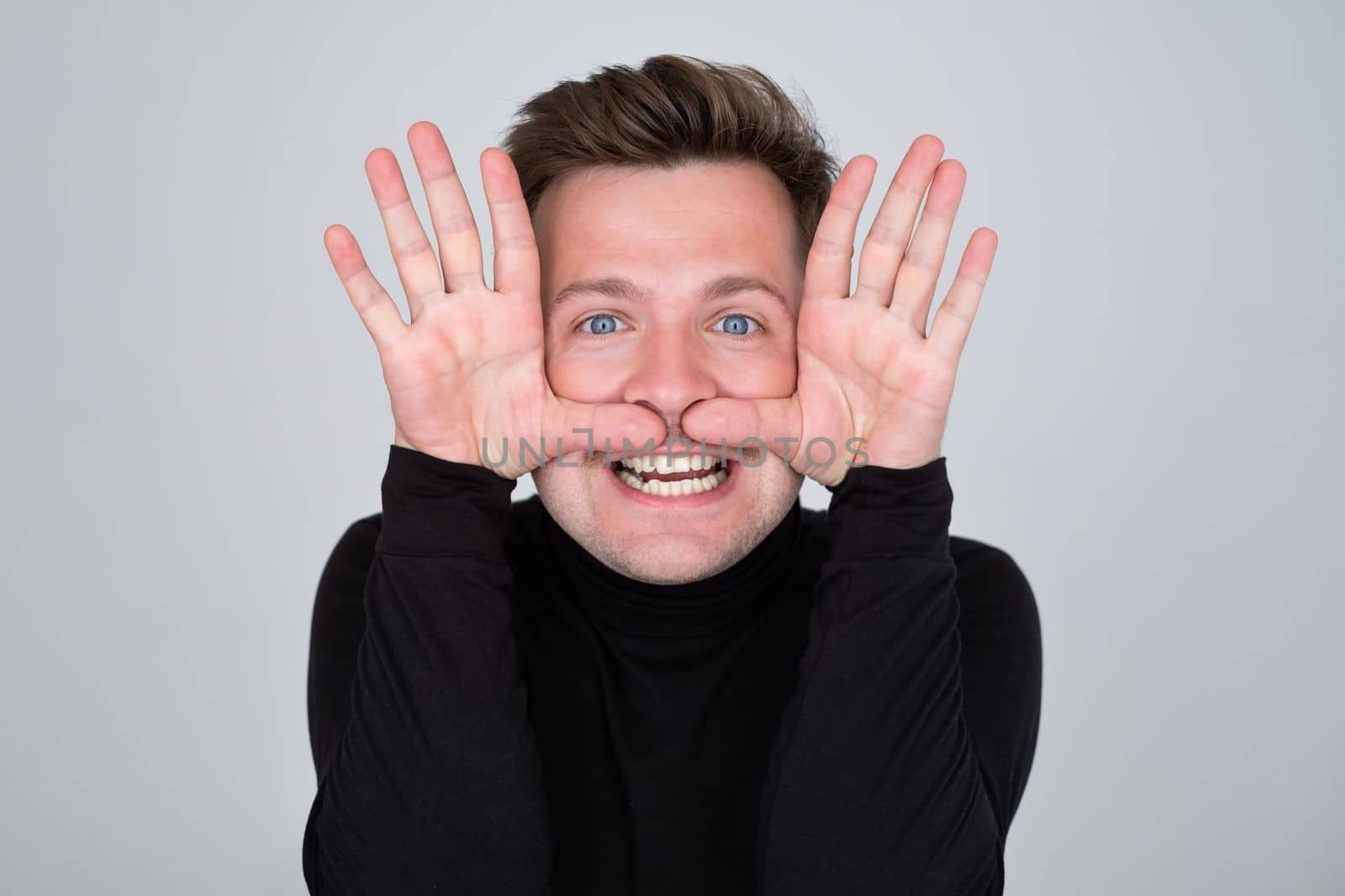 Funny young Caucasian man grimacing, having stupid and ridiculous facial expression.