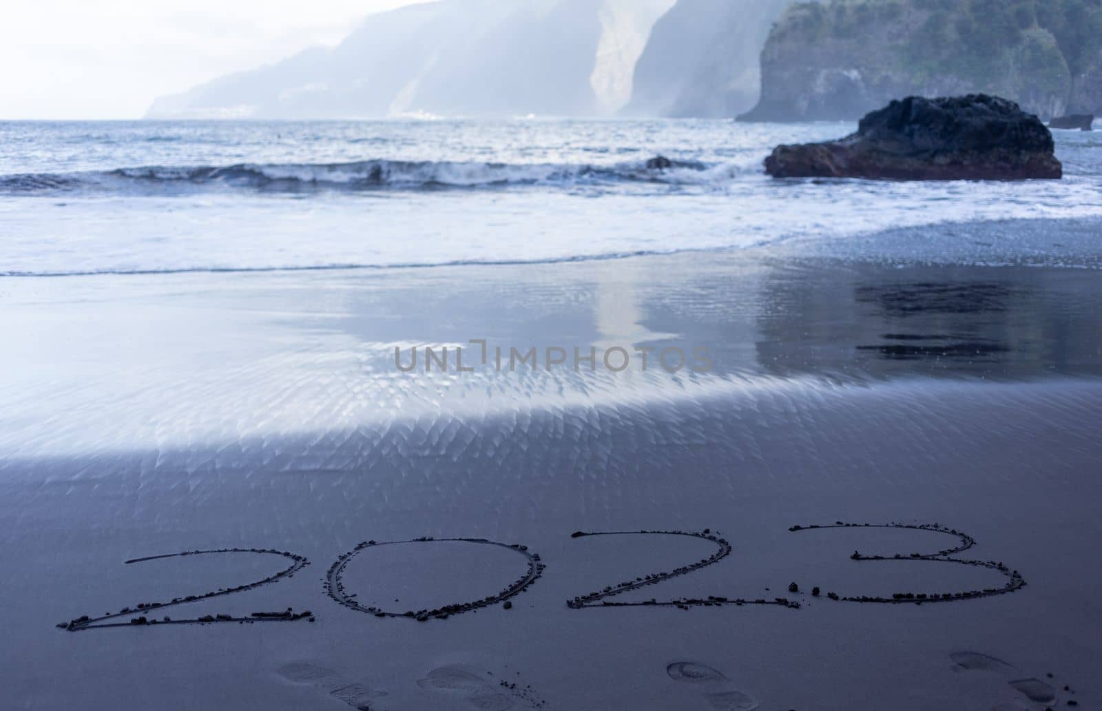 Year 2023 symbol written on black beach sand. High quality photo