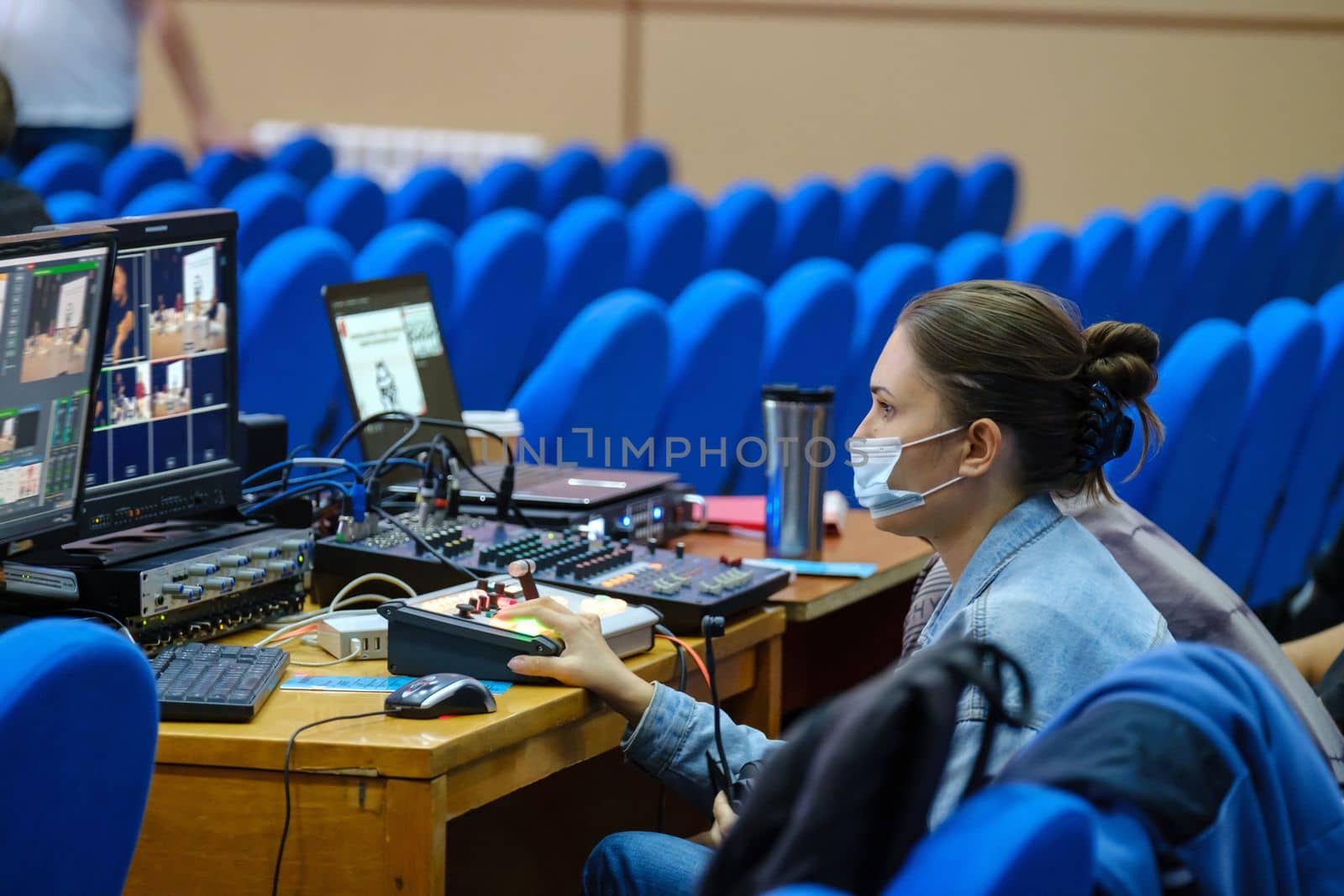 Young woman video editor in protective mask working on conference, seminar, use laptop editing video for streaming to internet, social media. download image