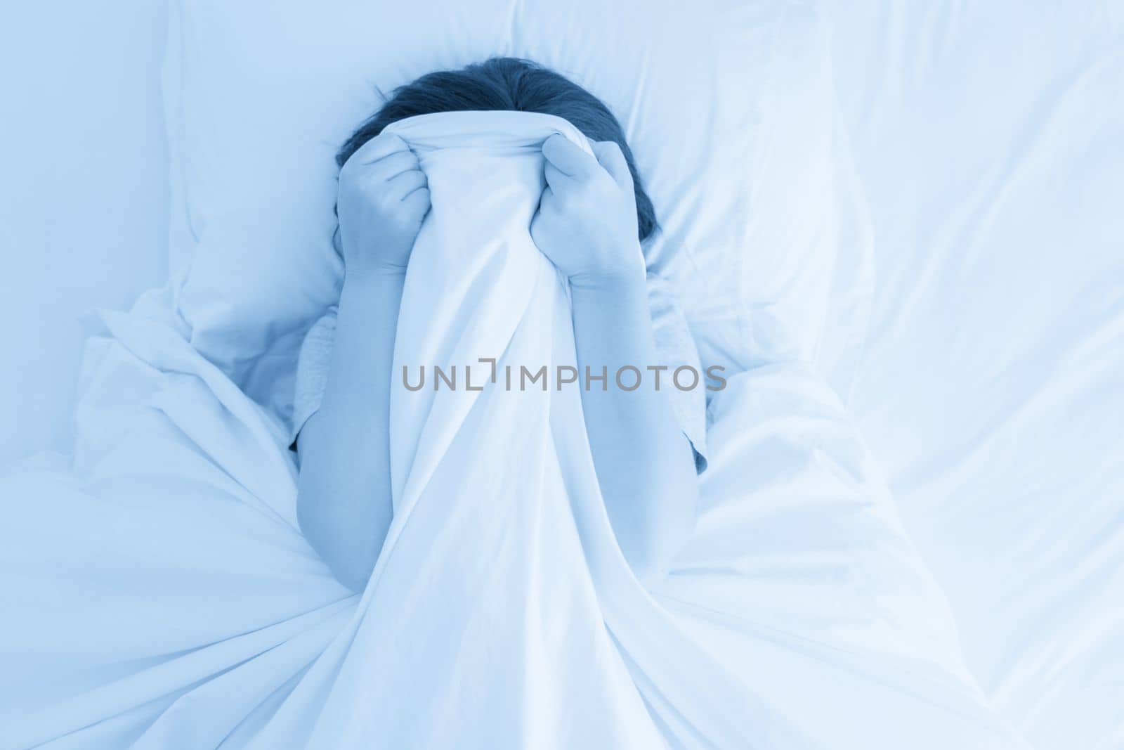 young woman laying in bed hiding her face by Mariakray
