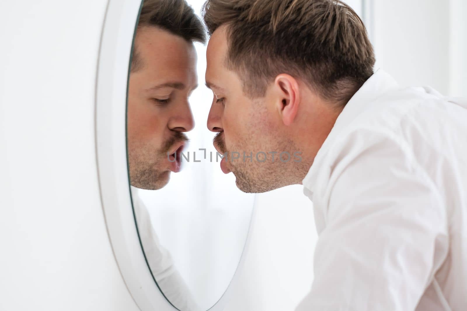 Unhappy businessman leaning on mirror trying to calm down getting bad news. Midlife crisis