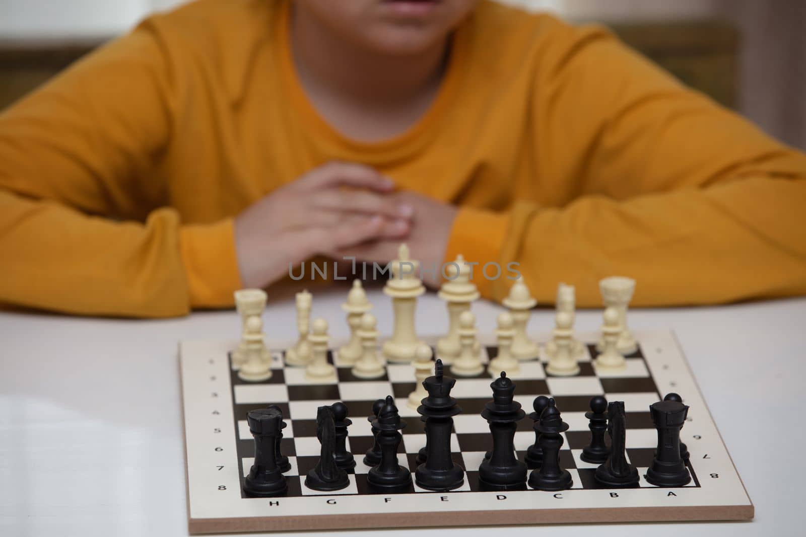 Chess board on table in front of school boy thinking of next move, tournament