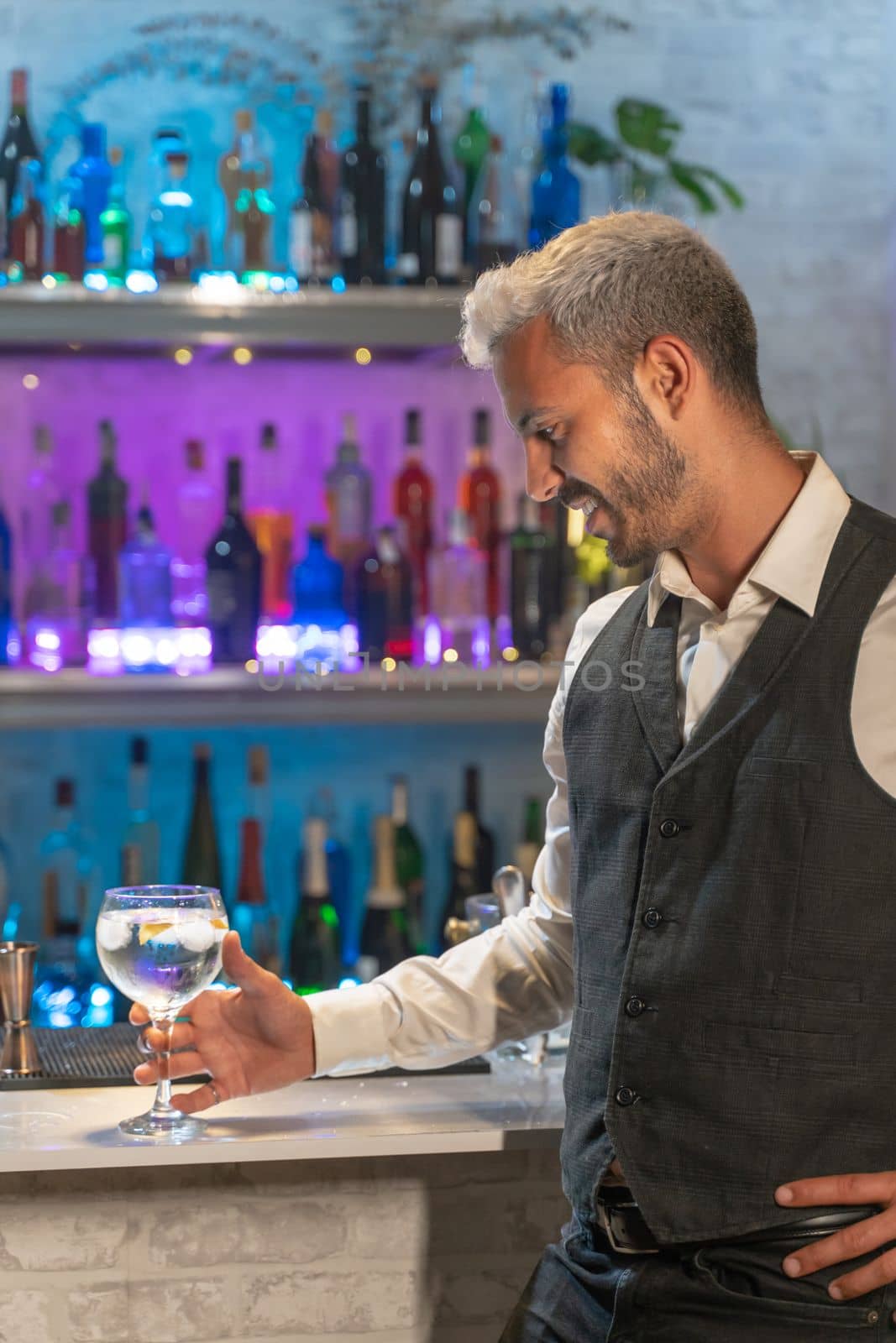 Professional barman tasting cocktail in nightclub. Night life concept. Vertical photo. High quality photo