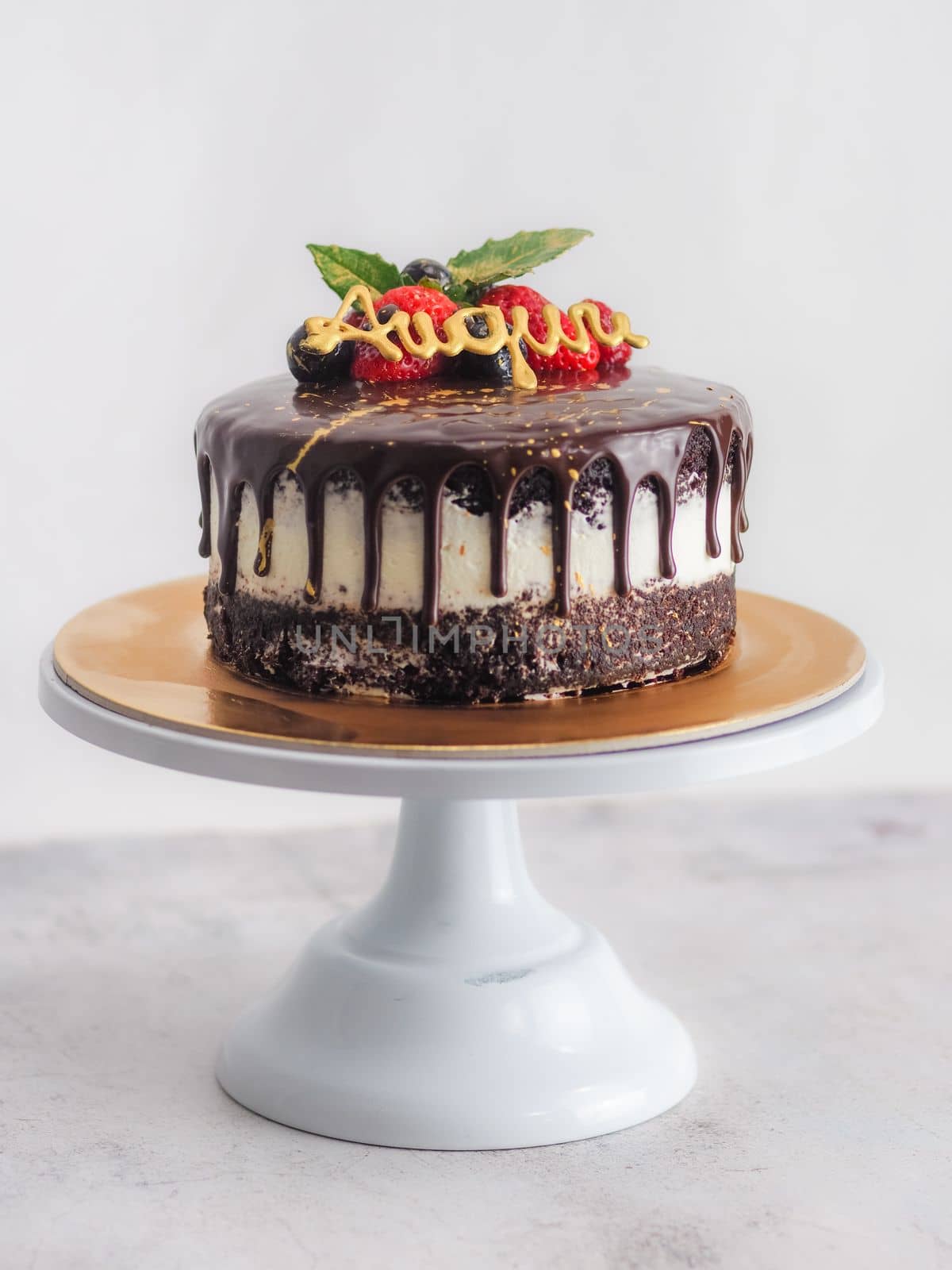 dark chocolate drips birthday sweet cake, fresh fruits Raspberry strawberry blueberry cranberry on top, decorated with golden edible paint