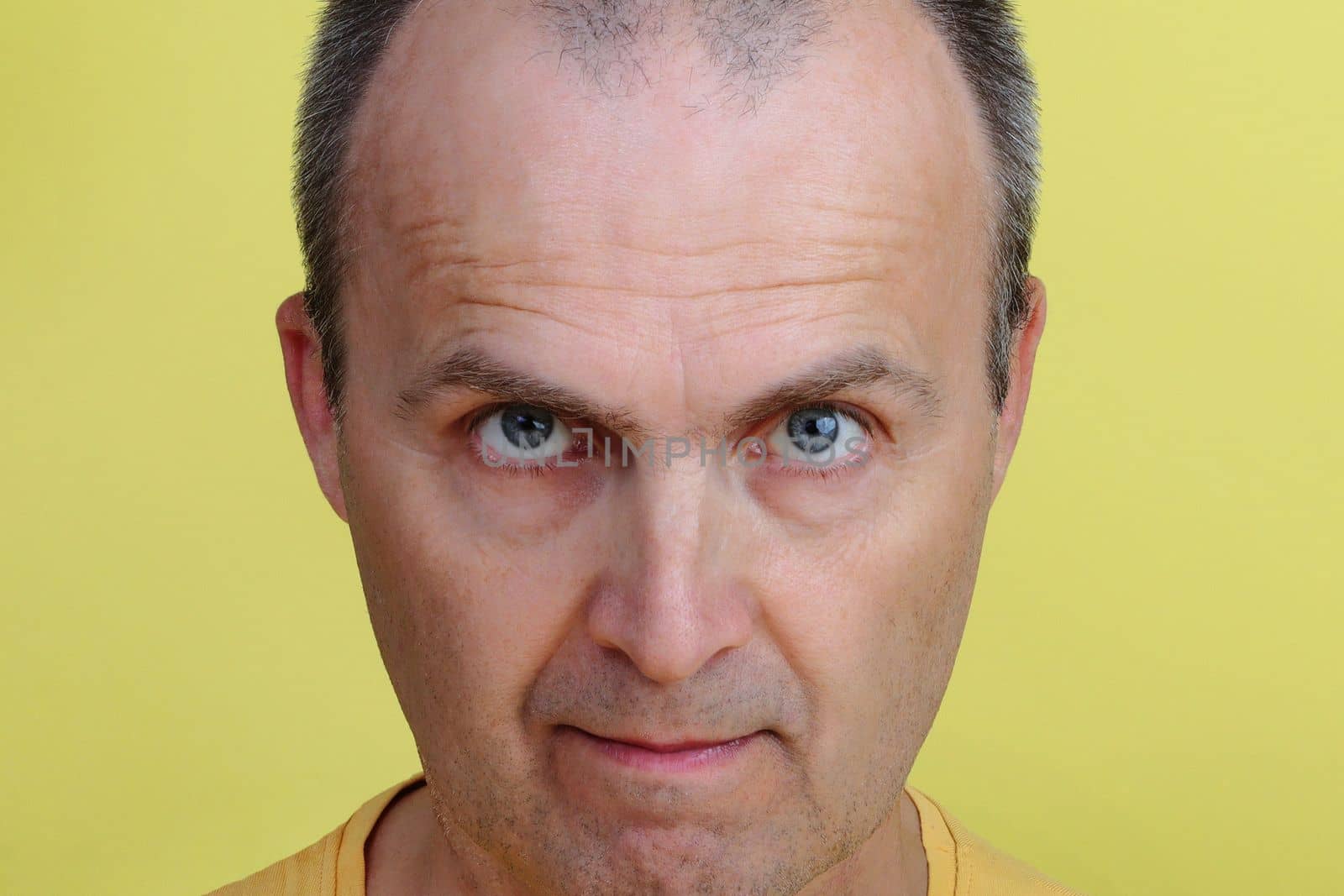 Close-up portrait of a handsome man 45-55 years old on a yellow background.