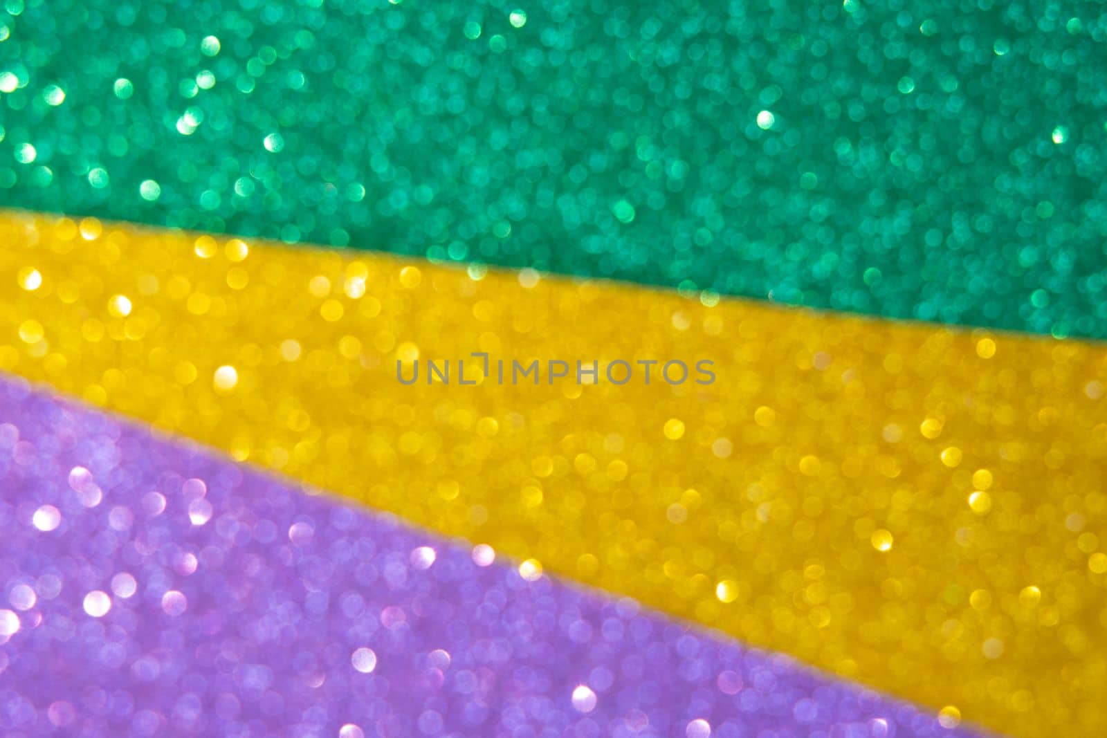 Mardi gras festive traditional color background. Abstract defocused shiny background gold, green, purple. Glow glitter Mardi gras celebration