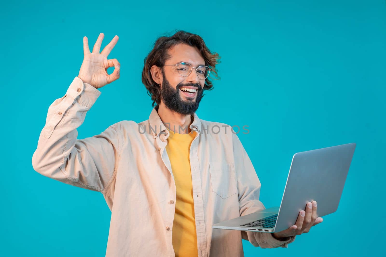 Portrait of a man holding laptop computer and celebrating success isolated over blue background by PaulCarr