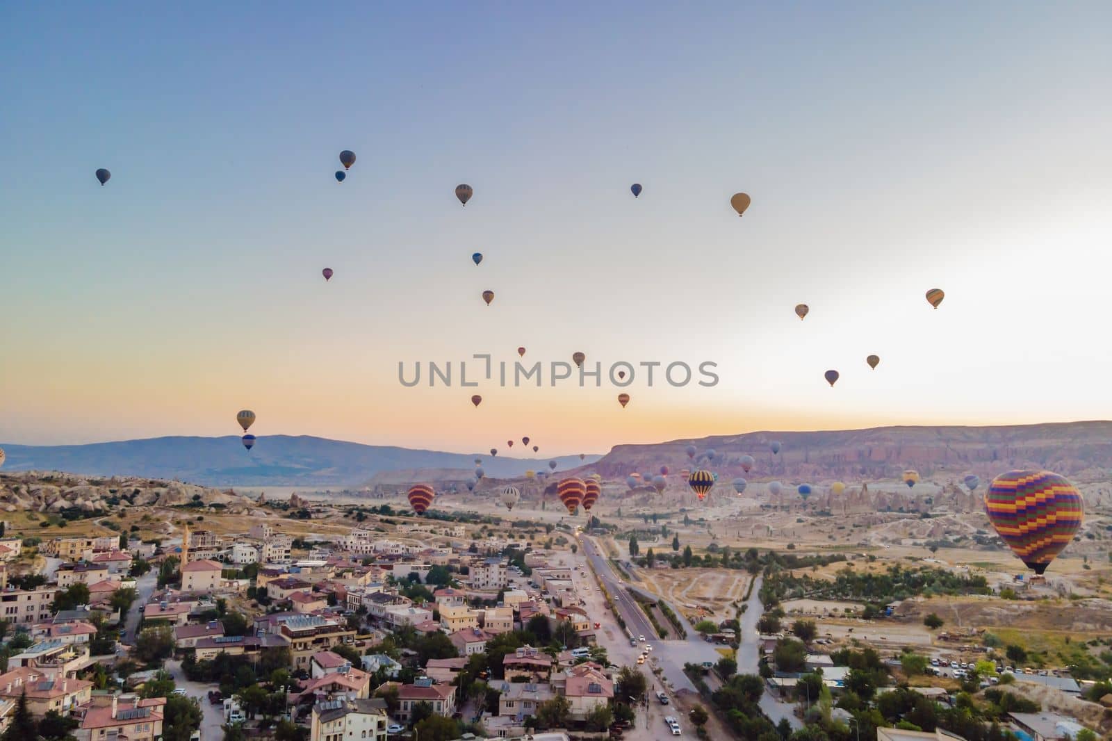 Colorful hot air balloons flying over at fairy chimneys valley in Nevsehir, Goreme, Cappadocia Turkey. Spectacular panoramic drone view of the underground city and ballooning tourism. High quality by galitskaya